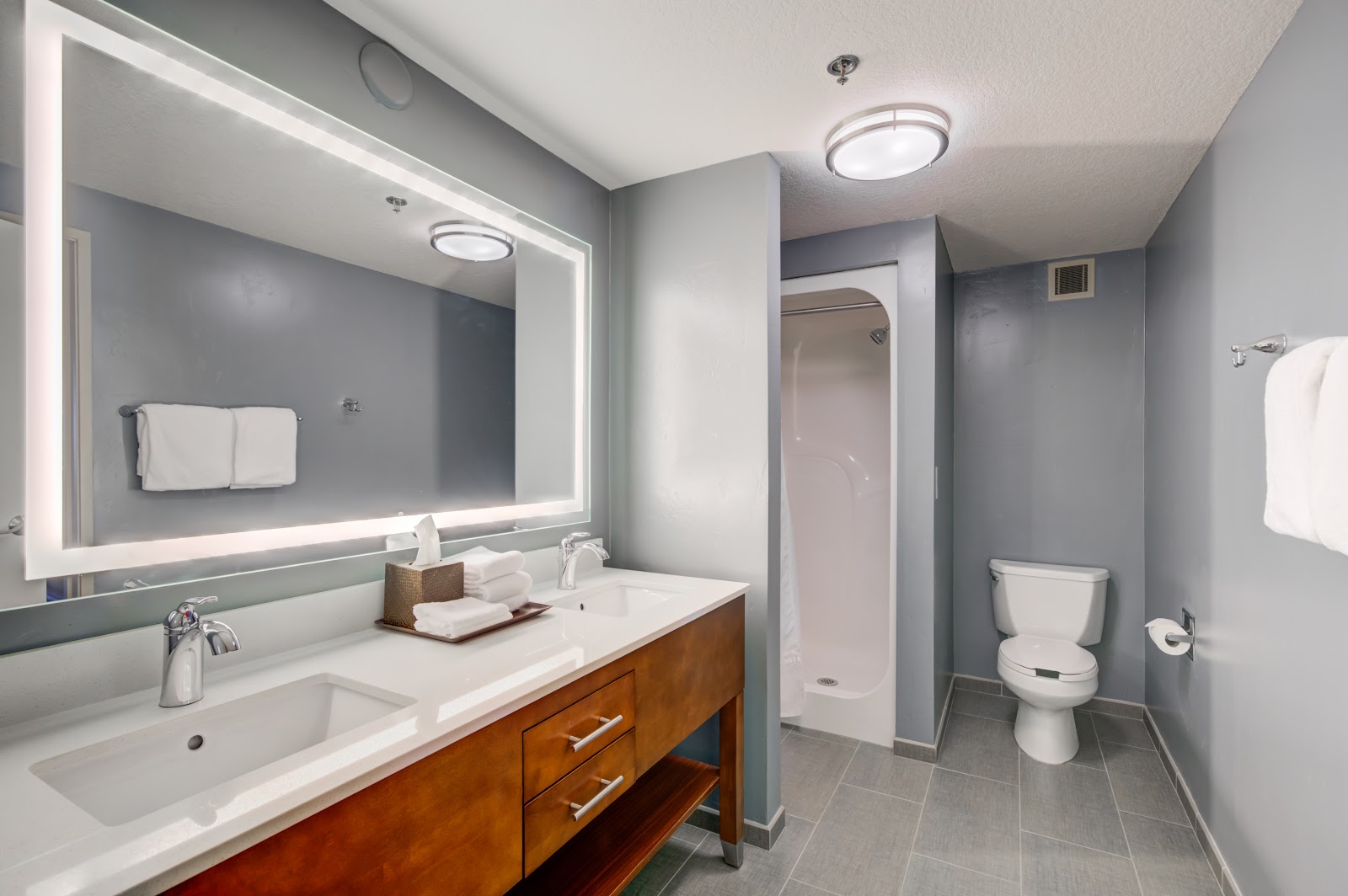 Guest bathroom in Glacier National Park lodging, featuring double sinks, a large illuminated mirror, and modern fixtures.
