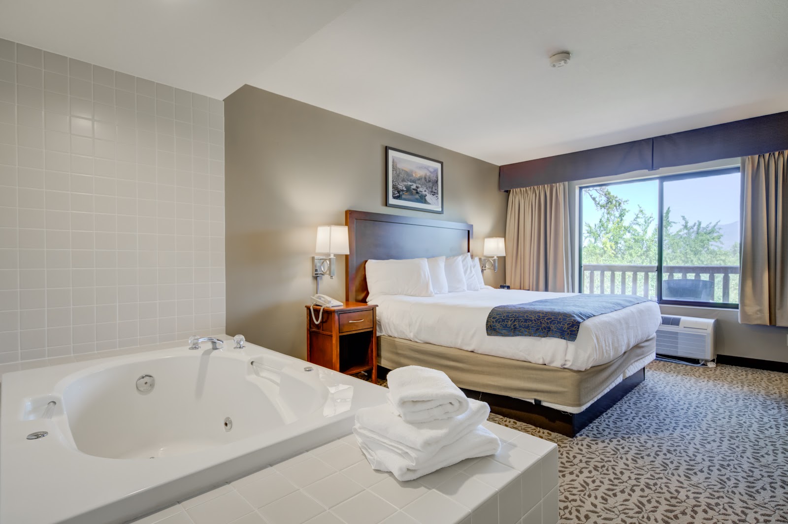 Luxurious Whitefish Riverfront Hotel guest room in Glacier National Park with a large in-room spa tub and plush bedding.