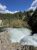 Upper Falls View in Yellowstone National Park shows a plunging turquoise river between rocky cliffs with a rainbow above.