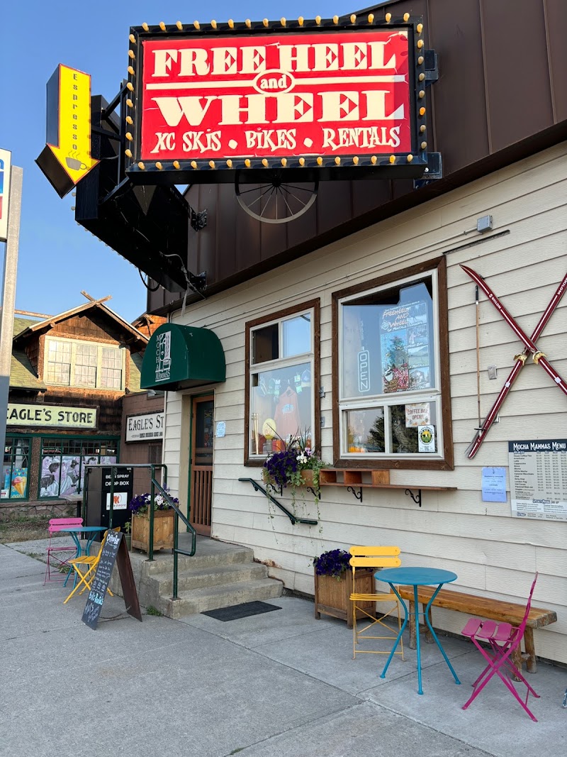 Colorful storefront in Yellowstone National Park town with a large red neon sign, skis crossed on the wall, and bright outdoor seating.