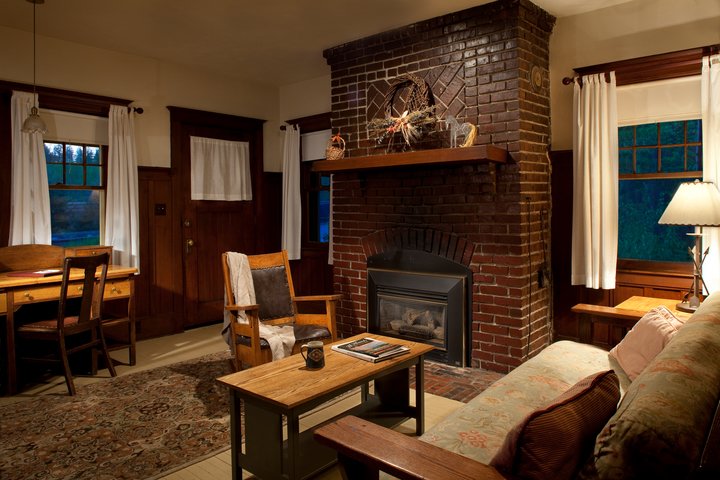 Cozy lodge lobby in Glacier National Park with brick fireplace, warm seating, and rustic decor.