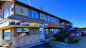 Facade of a budget motel with a parking lot and illuminated signage at dusk