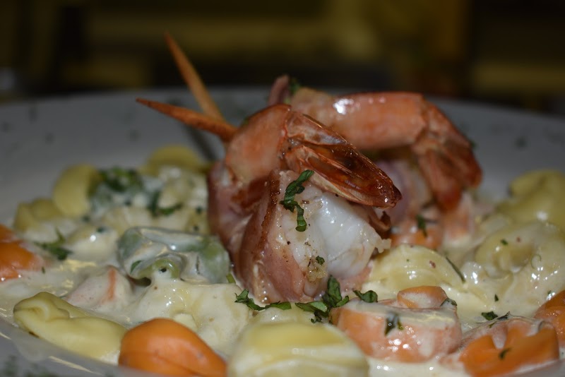 Creamy seafood pasta with large shrimp on top, salmon chunks, vegetables, and parsley, served in Yellowstone National Park.