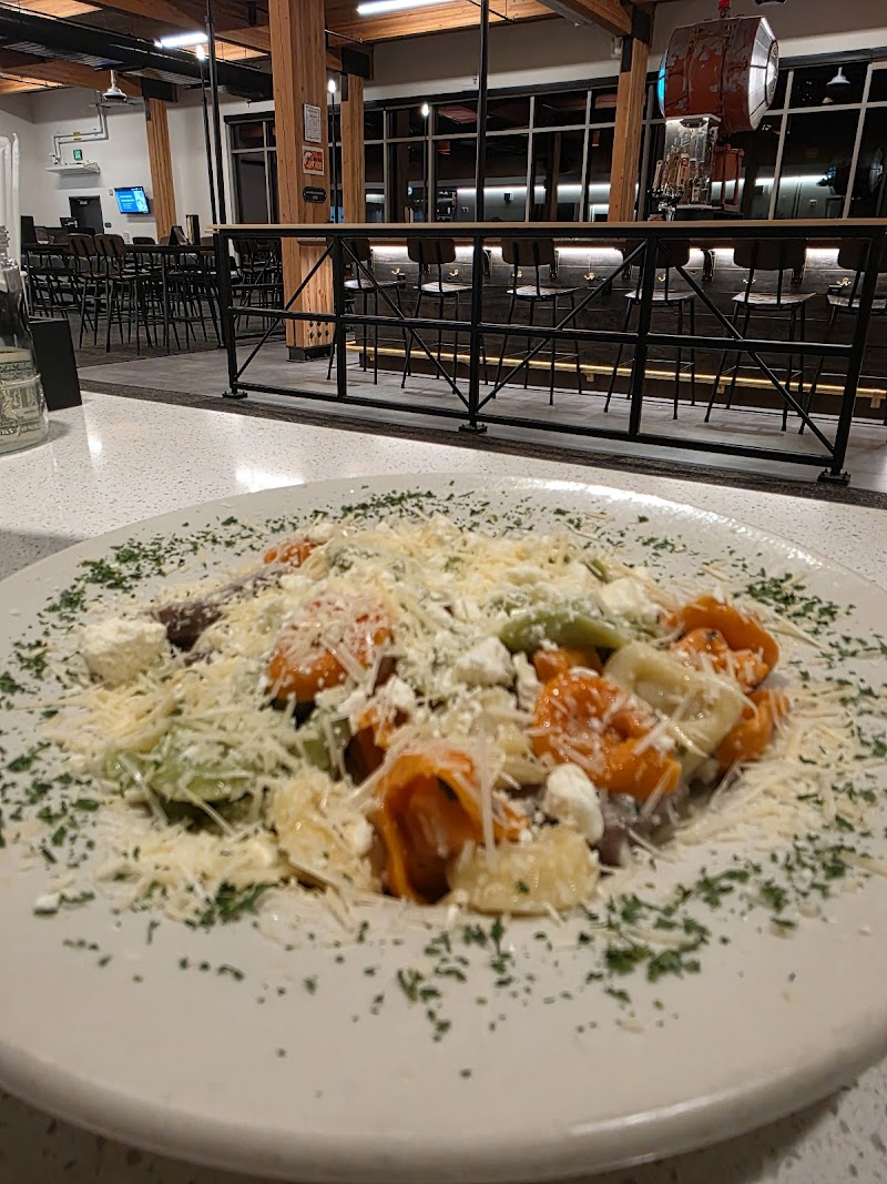 Creamy vegetable pasta with grated cheese served on a white plate in a Yellowstone National Park restaurant/bar area.
