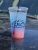 Blue-to-pink gradient drink cup with straw at Glacier National Park, featuring a mountain logo