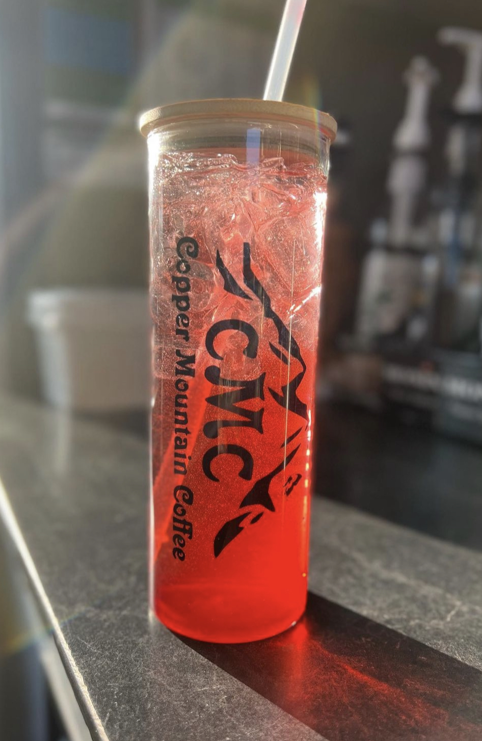 Red iced beverage in a glass with straw at a Glacier National Park cafe counter.