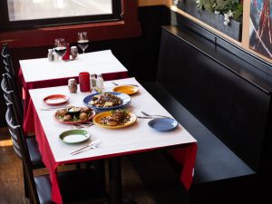 Dining tables at Mambo - Mountain Italian in Glacier National Park feature colorful plates and a sunlit window.