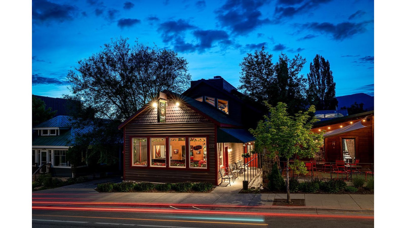 Mountain Italian restaurant storefront in Glacier National Park shown at twilight with outdoor seating along the street.