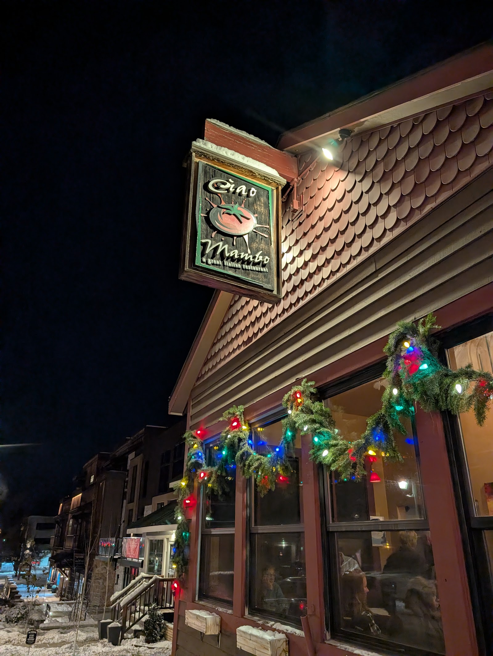 Festive restaurant exterior in Glacier National Park’s village, warmly lit with colorful holiday lights.