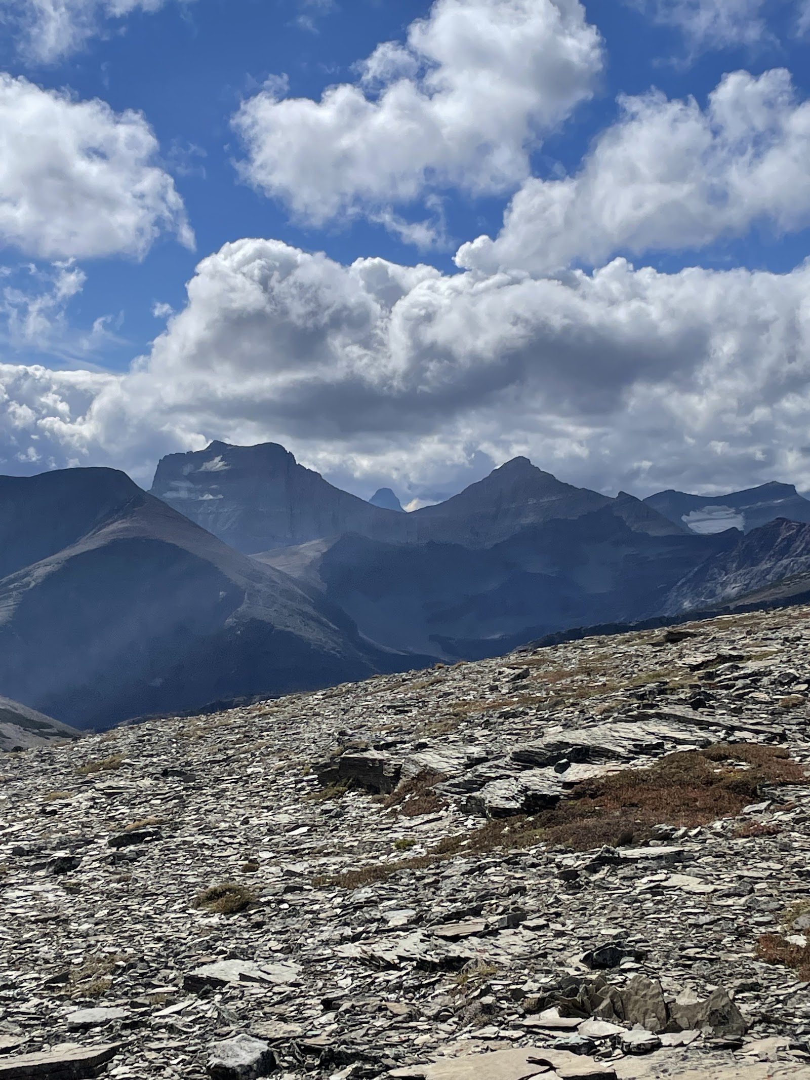 Rocky ridge overlook on Matahpi Peak in Glacier National Park, with jagged peaks and a bright blue sky.