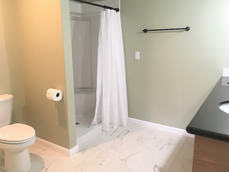 Bathroom interior in a Glacier National Park lodge with green walls, white shower curtain, and marble-like flooring.