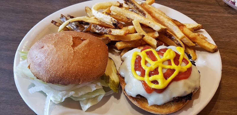 Plate features a cheeseburger with melted cheese, tomato, and mustard lattice, plus a side of fries in Yellowstone National Park.