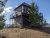 Apgar Lookout Trailhead viewpoint in Glacier National Park features a rustic wooden lookout building atop a rocky hill with surrounding pines.