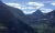 View from Glacier National Park showing a dramatic alpine valley flanked by jagged peaks under a blue sky.
