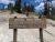 Wooden sign for Dragon's Mouth Spring on a sandy slope with pine trees and blue sky in Yellowstone National Park.