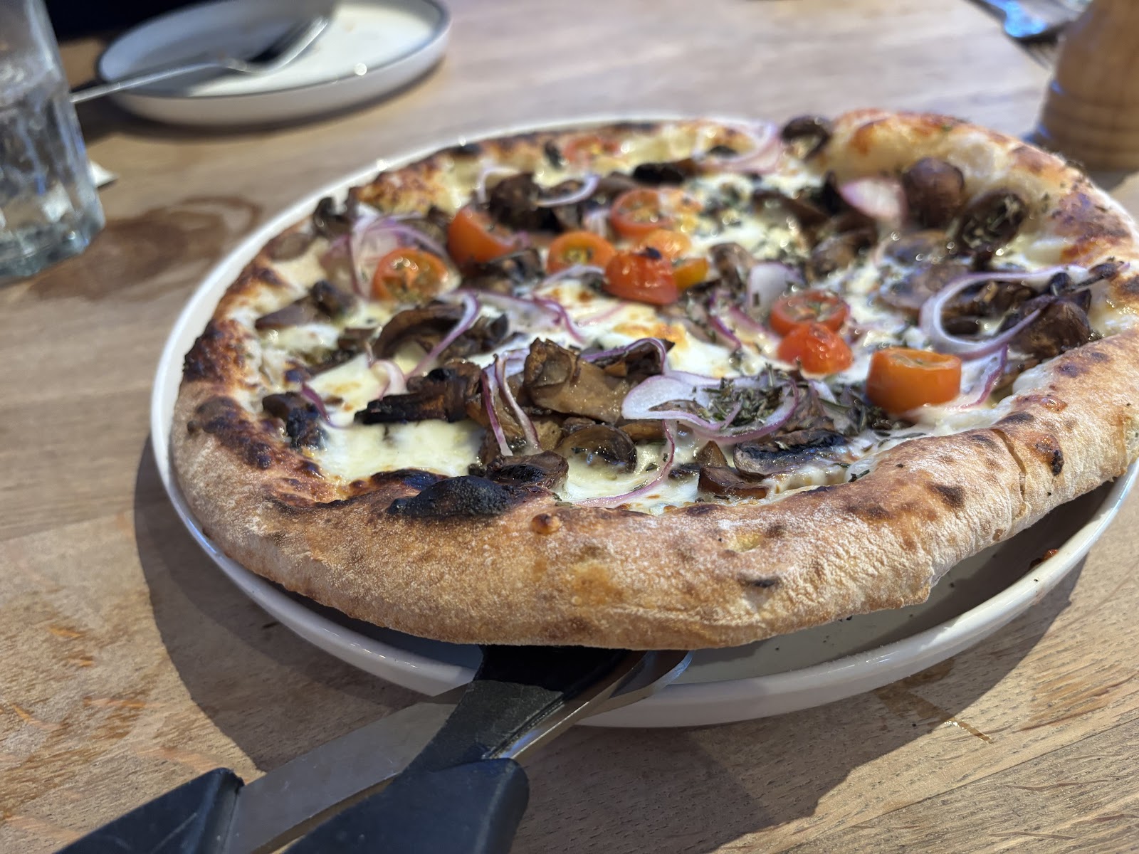 Cheesy pizza topped with mushrooms, onions, and cherry tomatoes from Glacier National Park restaurant setting.