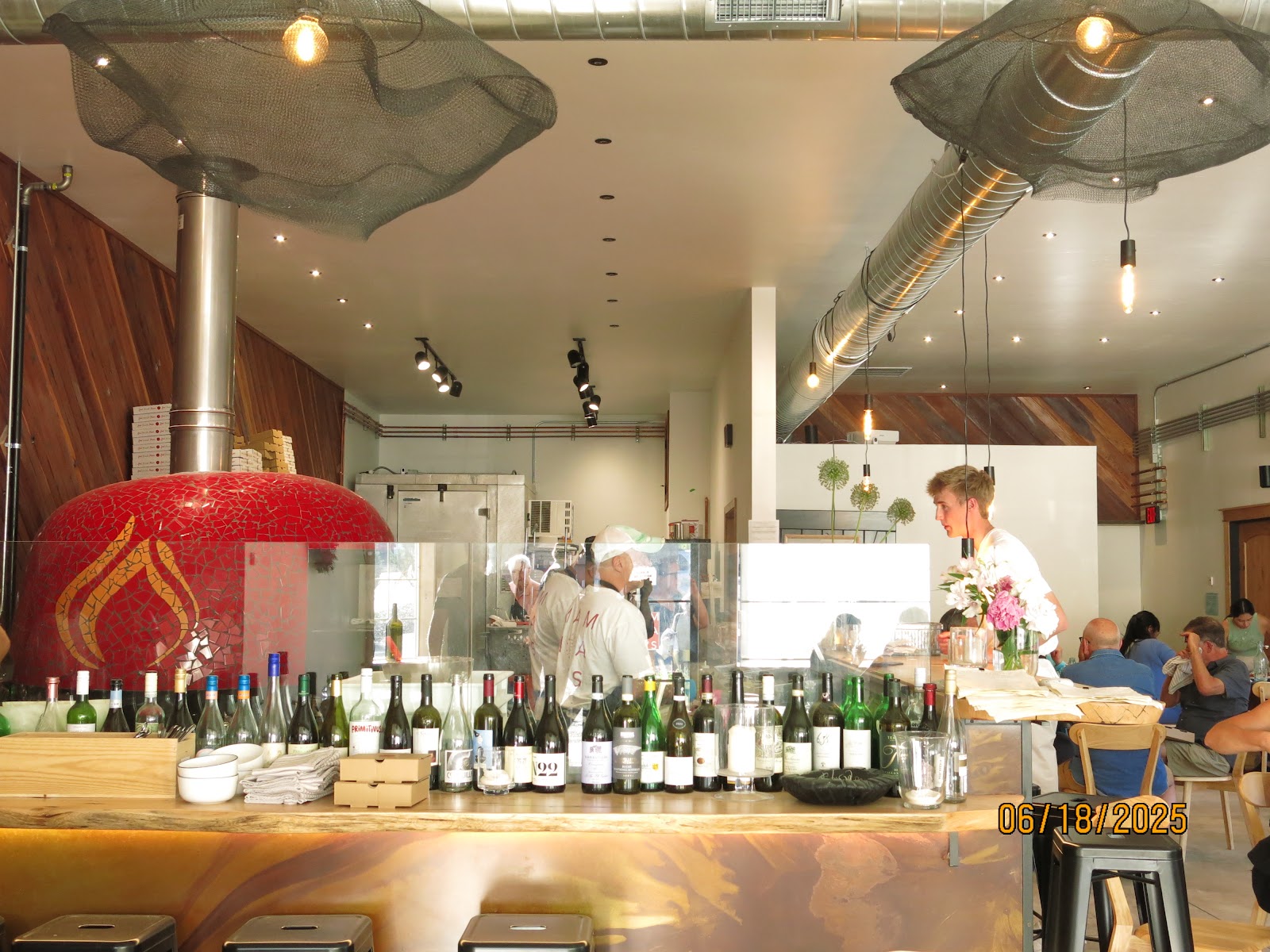 Interior view of Mama Ev's Pizzeria at Glacier National Park, showing a long bar lined with bottles and an open kitchen.