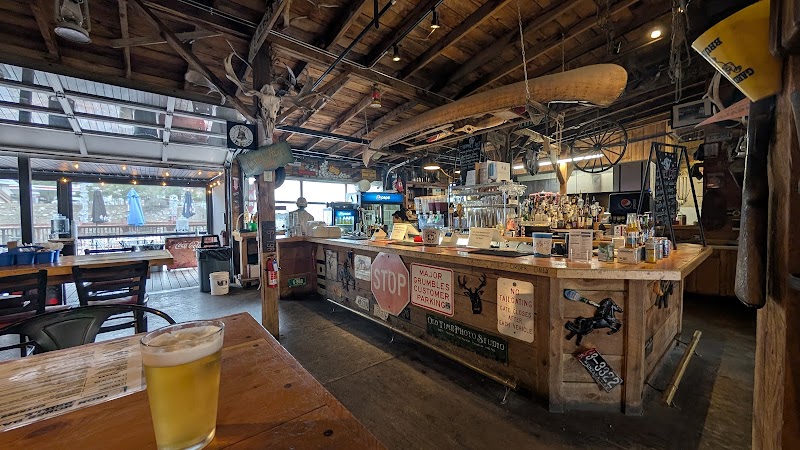 Rustic bar inside a wooden lodge with a long counter, beer on the table, wagon-wheel decor, and bottled shelves in Yellowstone National Park.