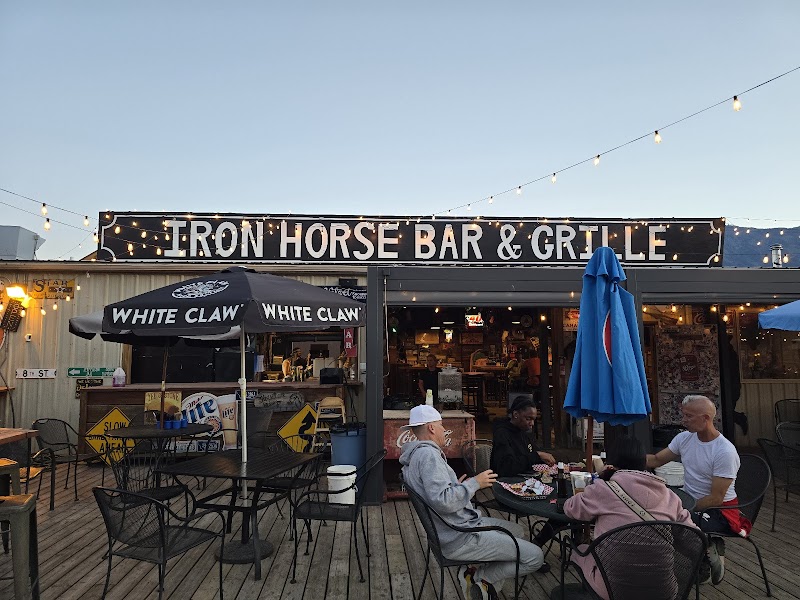 Outdoor dining on a wooden deck with string lights, umbrellas, and people seated at tables in a bar and grill in Yellowstone National Park.