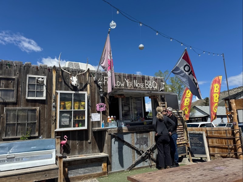 Rustic wooden BBQ shack with antlers, string lights, and a couple chatting outside in Yellowstone National Park.