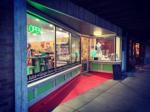 A vintage-style cafe storefront in Glacier National Park glows with a neon OPEN sign and colorful interior lighting.