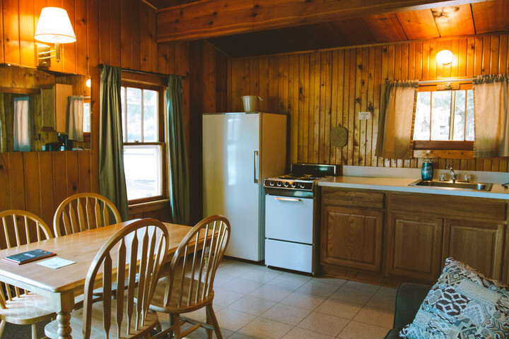 Rustic cabin kitchen in Glacier National Park’s Apgar Village area, with wooden walls and a full-size fridge.
