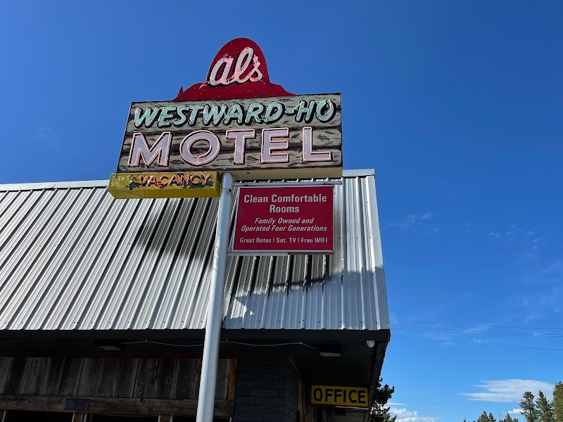 Vintage motel sign atop a weathered building with metal siding, blue sky in Yellowstone National Park.