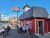 Red barn-style restaurant with outdoor picnic tables full of diners, flags, and a blue sky in Yellowstone National Park.