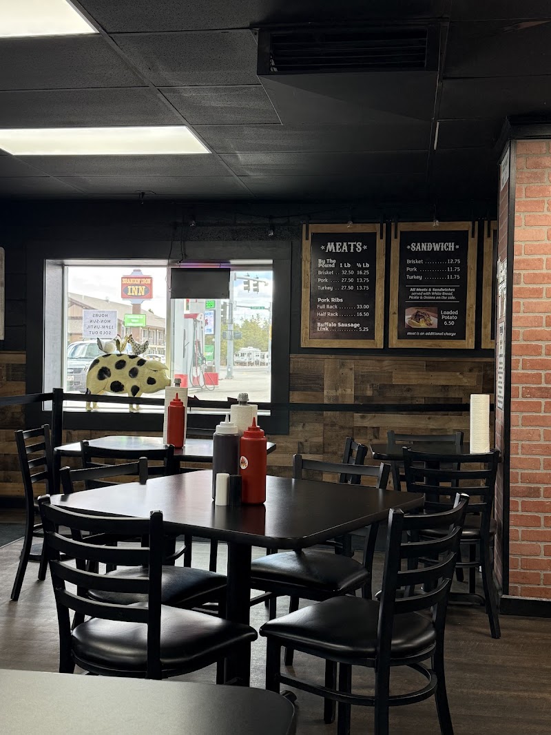 Casual Yellowstone National Park eatery interior with dark tables, black chairs, condiment bottles, and chalkboard menu boards.