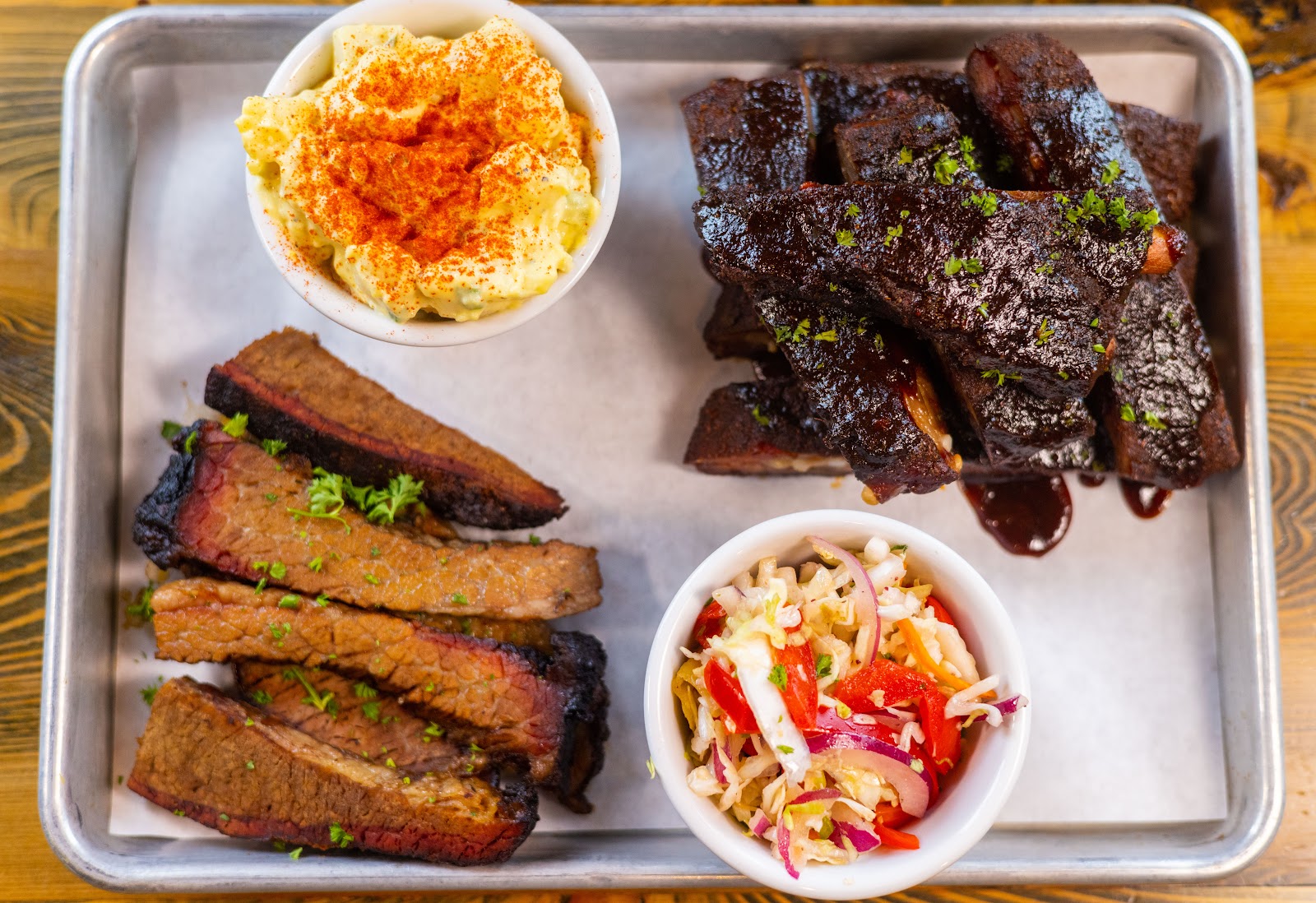 Barbecue ribs platter with mac and cheese and coleslaw on a metal tray, enjoyed at a Glacier NP dining spot.