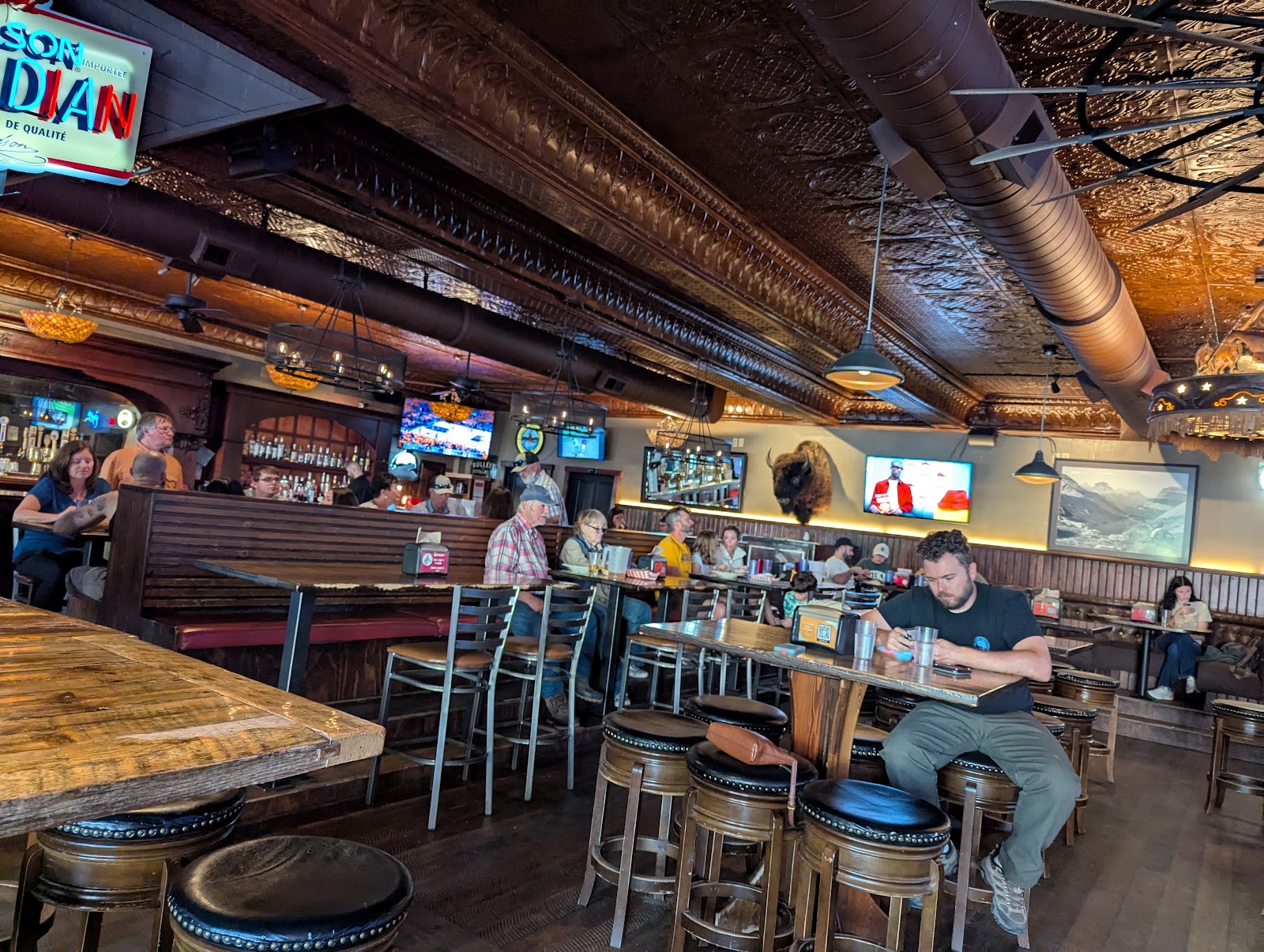 Interior view inside a rustic Glacier National Park saloon with wood booths and patrons.
