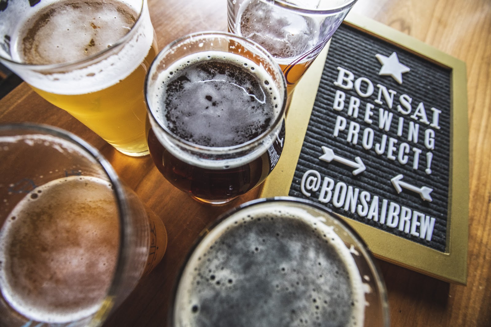 Taproom table at Glacier National Park featuring several craft beers and a nearby promotional sign.