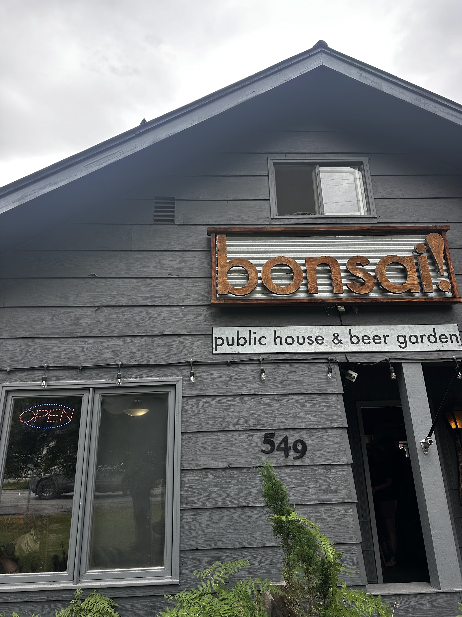 Exterior of a gray wood building housing a public house and beer garden in Glacier National Park.