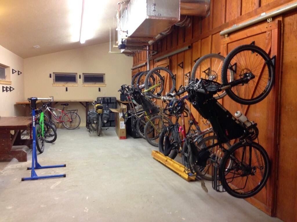Bike storage room at Glacier National Park lodging with wall-mounted racks and multiple bicycles organized along the wood-paneled wall.