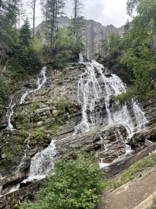 Bertha Trailhead in Glacier National Park features a cascading multi-stream waterfall along a rugged rock face.