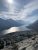 Bertha Trailhead overlook in Glacier National Park frames a winding lake with jagged mountains and a bright sky.