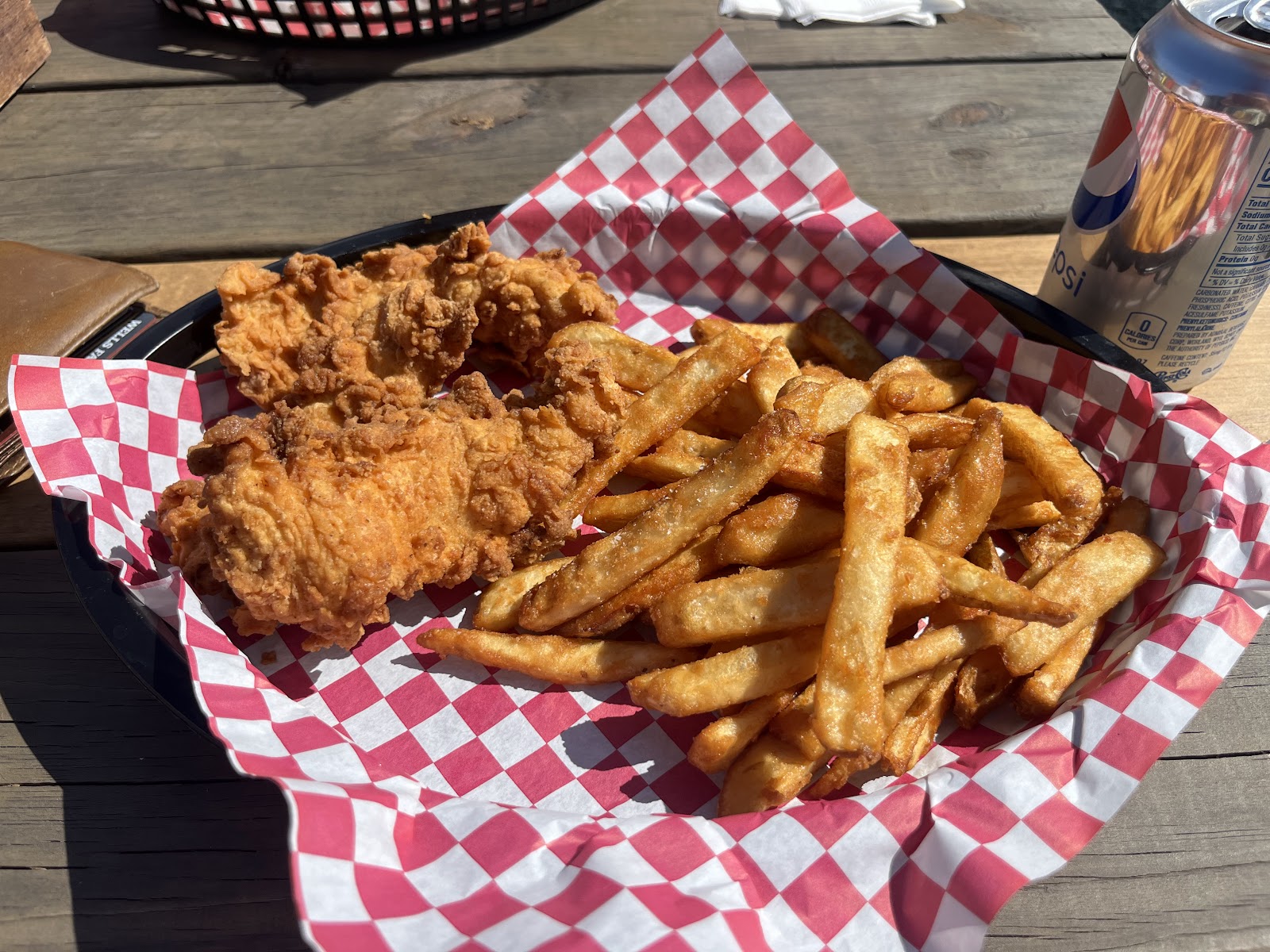 Crispy fried chicken and golden fries served on red-and-white checkered paper at Glacier National Park.