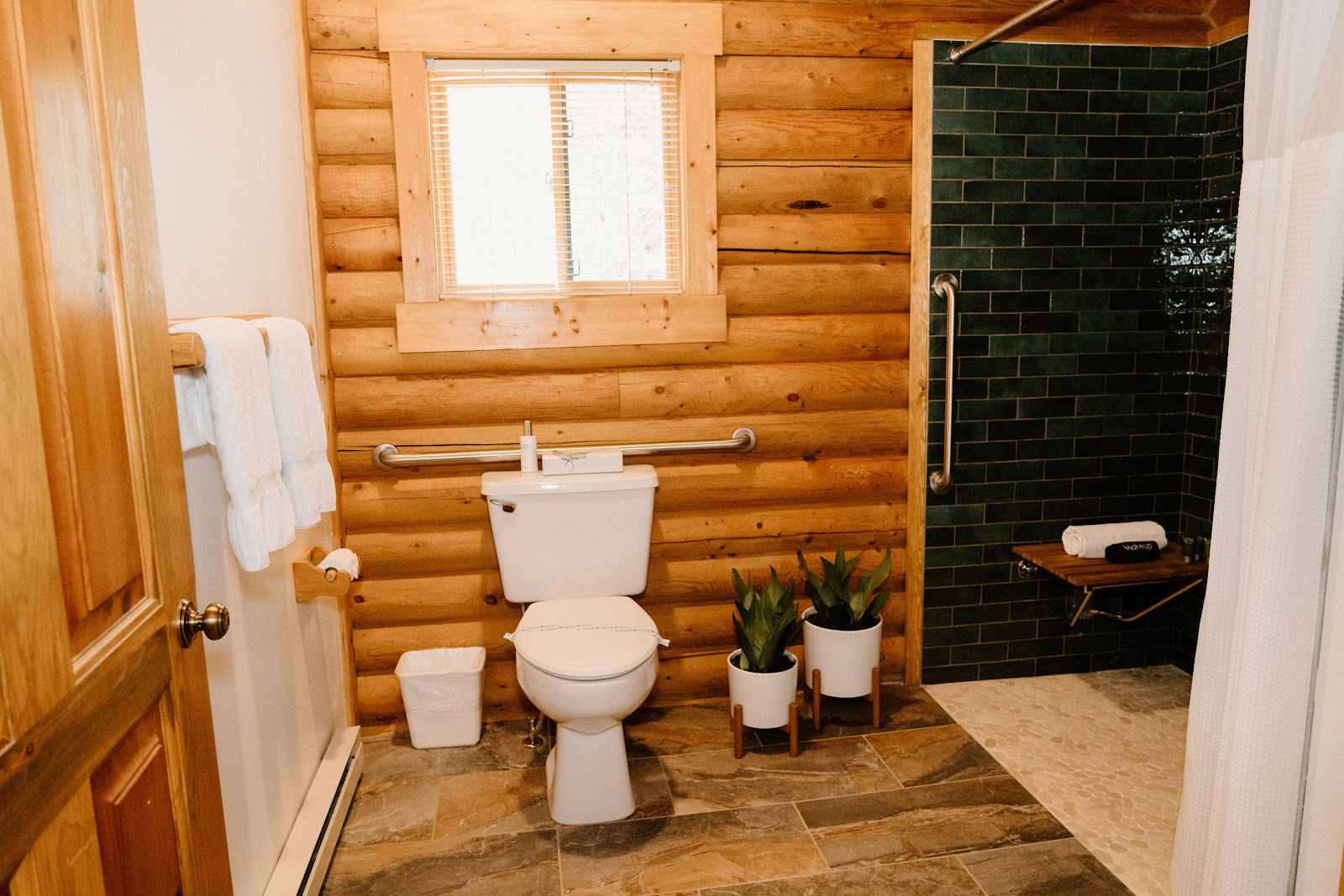 Log cabin bathroom in a Glacier National Park lodging unit with wooden walls and a compact toilet.