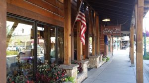 Gift shop storefront along a wooden veranda in Glacier National Park, with an American flag display and shop windows.