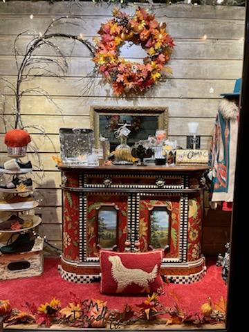 Interior of a Glacier National Park gift shop featuring an ornate red cabinet display and autumn wreaths.