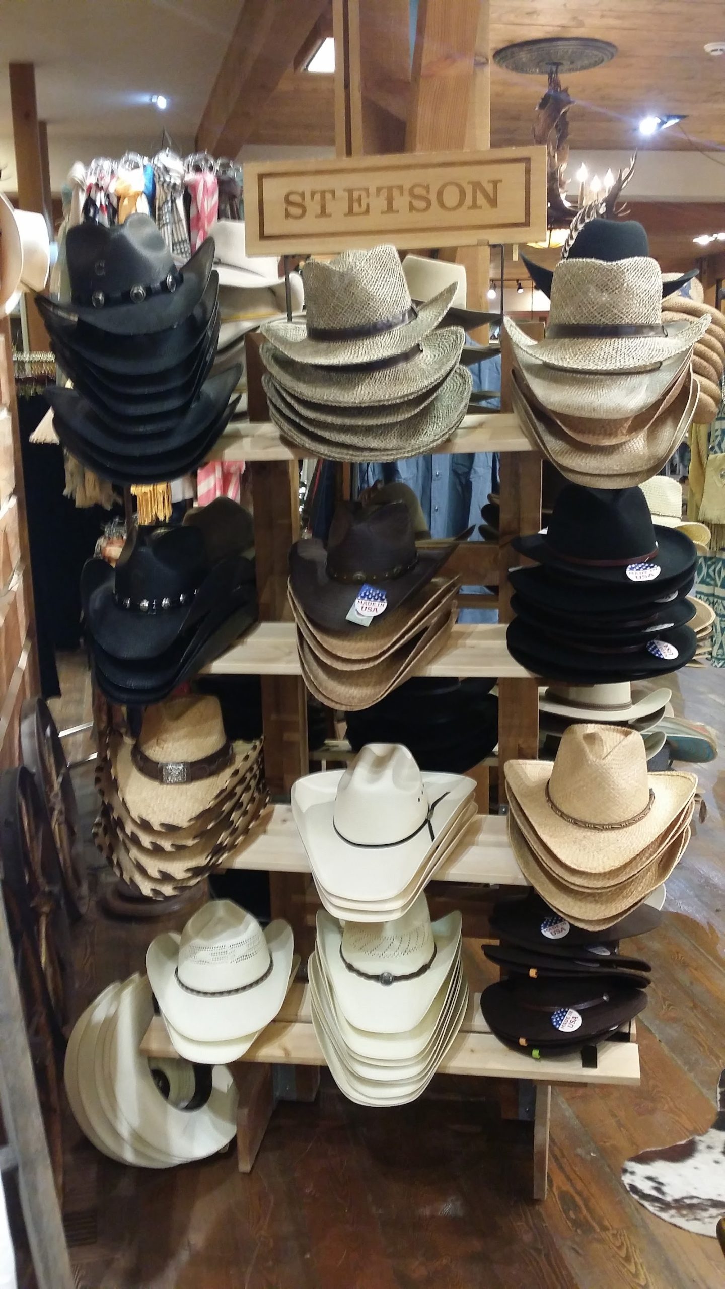 Stetson hat display in a Glacier National Park gift shop, featuring stacked cowboy hats on wood shelves beneath a rustic sign.