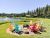 Colorful Adirondack chairs surround a fire pit beside a pond at a Glacier National Park lodging area.