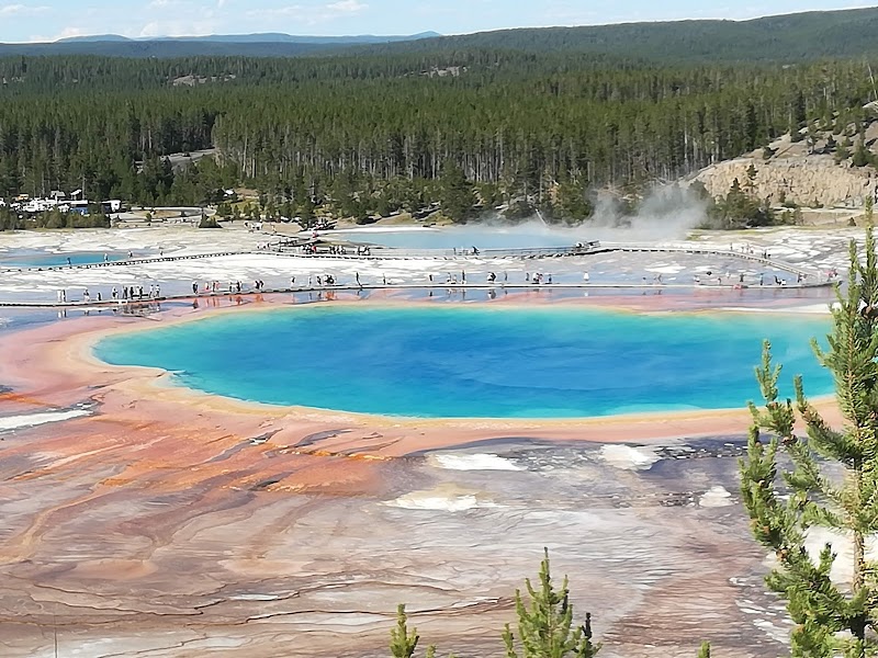 Vivid Grand Prismatic Spring with turquoise and orange-red rings, boardwalks and visitors in Yellowstone National Park.