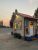 Small roadside espresso stand in Glacier National Park, decorated with autumn wreaths and string lights at dusk.