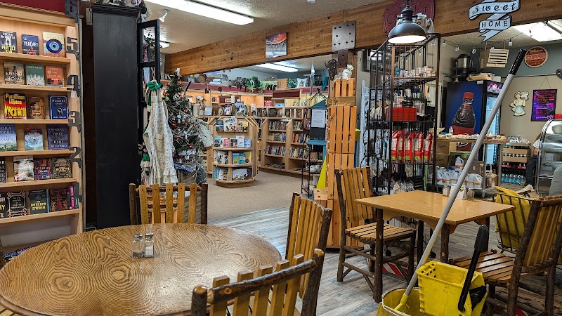Cozy gift shop and cafe interior with round wooden tables, chairs, and bookshelves inside Yellowstone National Park.