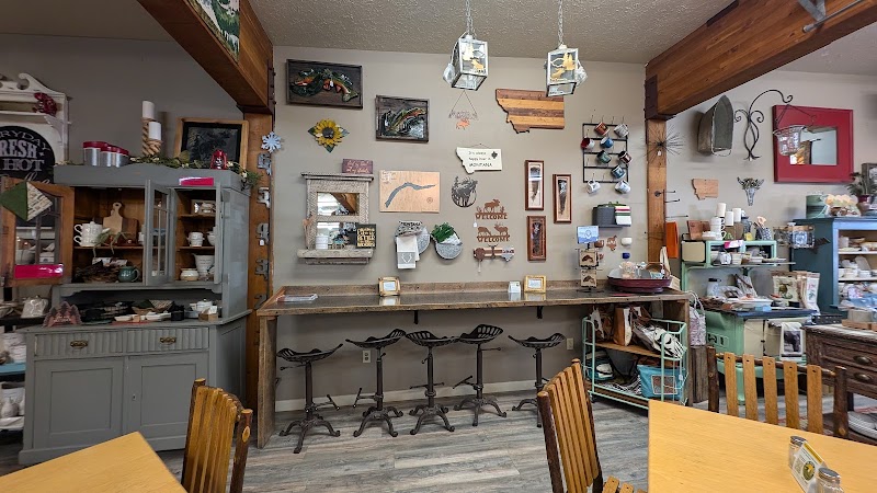 Cozy gift shop interior in Yellowstone National Park with a long wooden counter, wall decor, and metal stools at the bar.