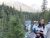 Family at McDonald Falls overlook in Glacier National Park, posed on a rocky ledge with a pine forest backdrop.