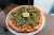 Pizza topped with arugula and a lemon wedge on a round metal tray at Glacier National Park restaurant.