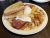Breakfast plate with two sunny eggs, crispy bacon, hash browns, and toast in Glacier National Park.