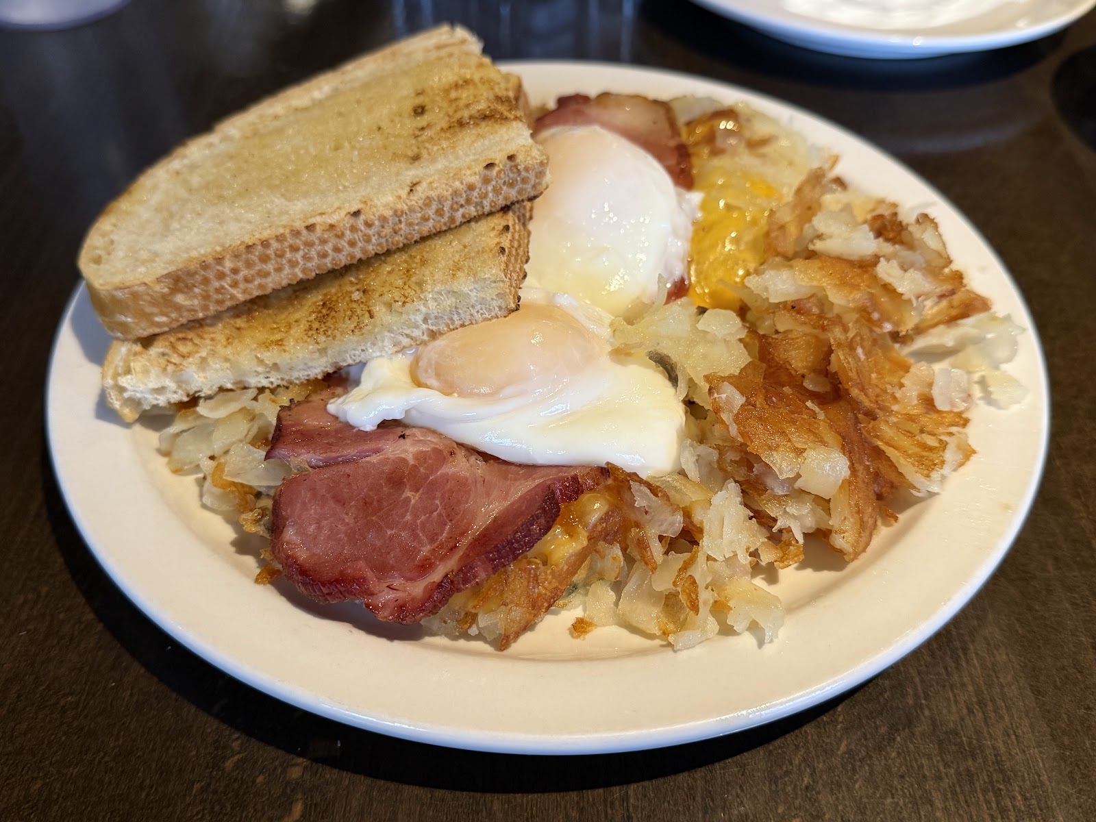 Breakfast plate with two sunny eggs, crispy bacon, hash browns, and toast in Glacier National Park.